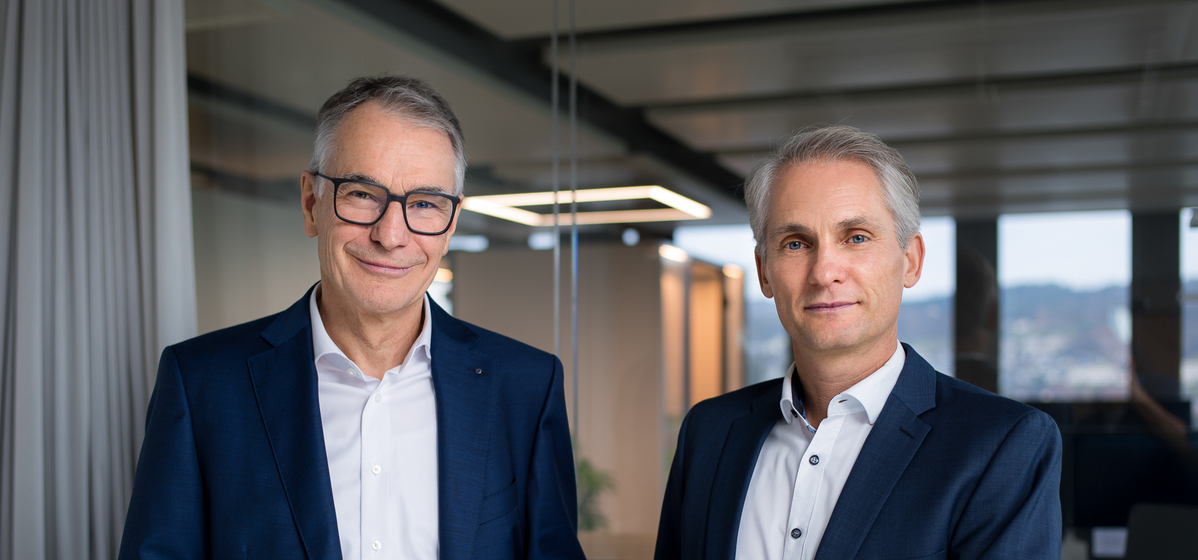 Photo of former CEO Martin Becker and new CEO Alexander Heizler standing together. 