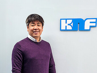 KNFロゴとKNF Koreaのシニアセールスエンジニアで水素及び燃料電池ポンプの専門家であるジン・キハン氏。