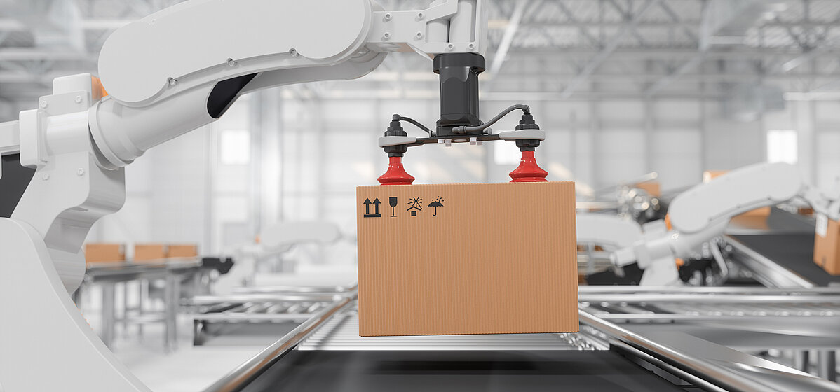 Side view of a white robotic arm with red vacuum grippers carrying a cardboard box on a conveyor belt in a smart distribution warehouse