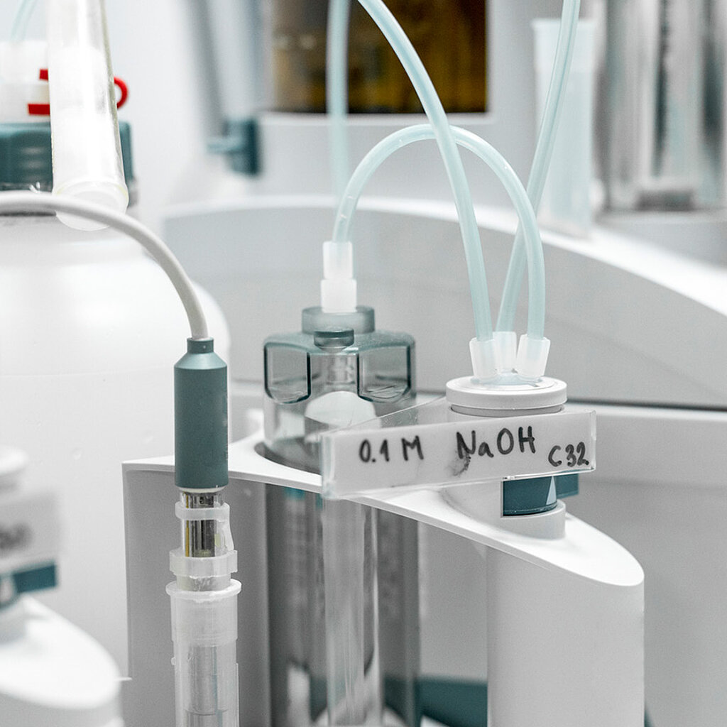 Laborgeräteaufbau mit verschiedenen Leitungen, die Medien aus unterschiedlichen Behältern zu einem Analysegerät transportieren.