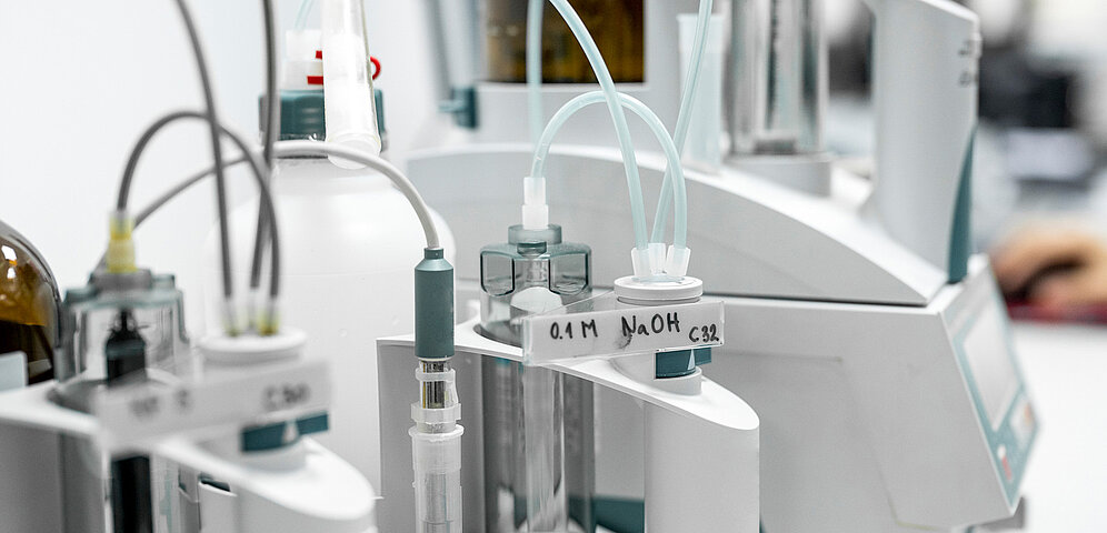 Laborgeräteaufbau mit verschiedenen Leitungen, die Medien aus unterschiedlichen Behältern zu einem Analysegerät transportieren.