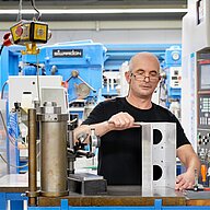 A metal worker at KNF Neuberger GmbH measuring the wall thickness of a diaphragm gas pump housing.