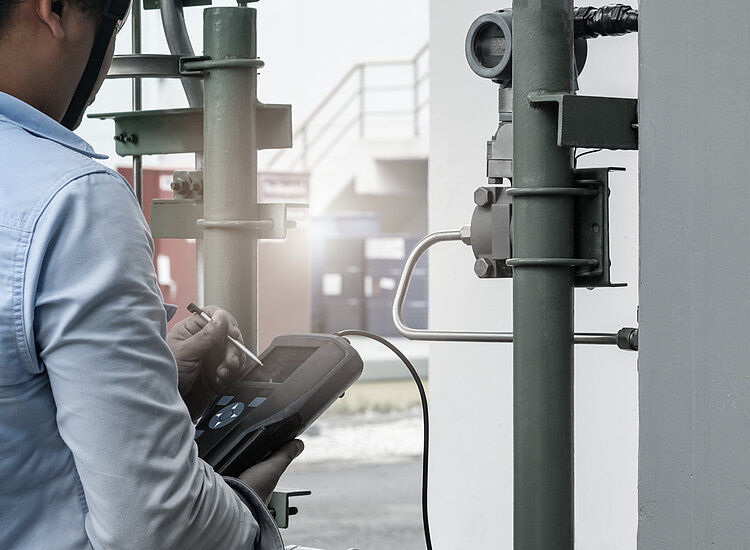 A worker reading a portable emission measurement device at an industrial facility