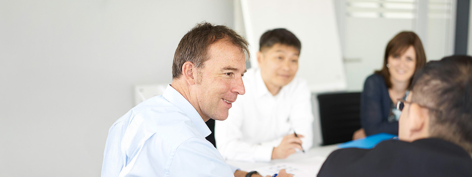 Three people are having a conversation in a KNF meeting room.